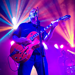 Rock-a-billy guitarist playing live with colourful background